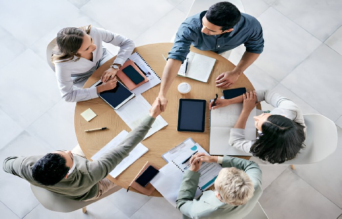 Five employees discussing what is resource forecasting at a conference desk